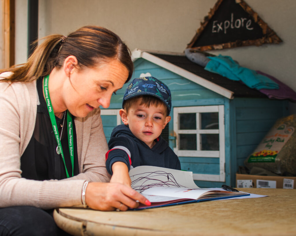 A teacher looking at a book with a young pupil.