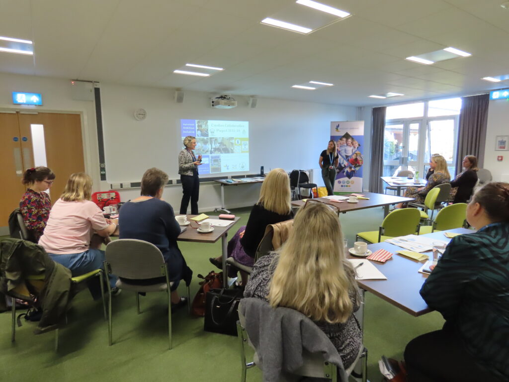 A person presenting to a group of people sat at a number of tables