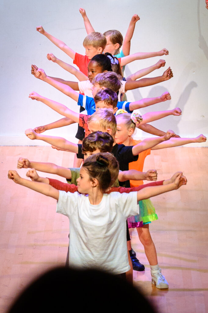 A group of children standing in a line with their arms out