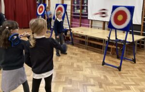 Two young girls standing Infront of an archery target board