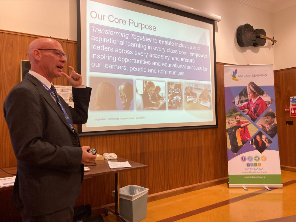 A man in a suit wearing glasses giving a presentation.