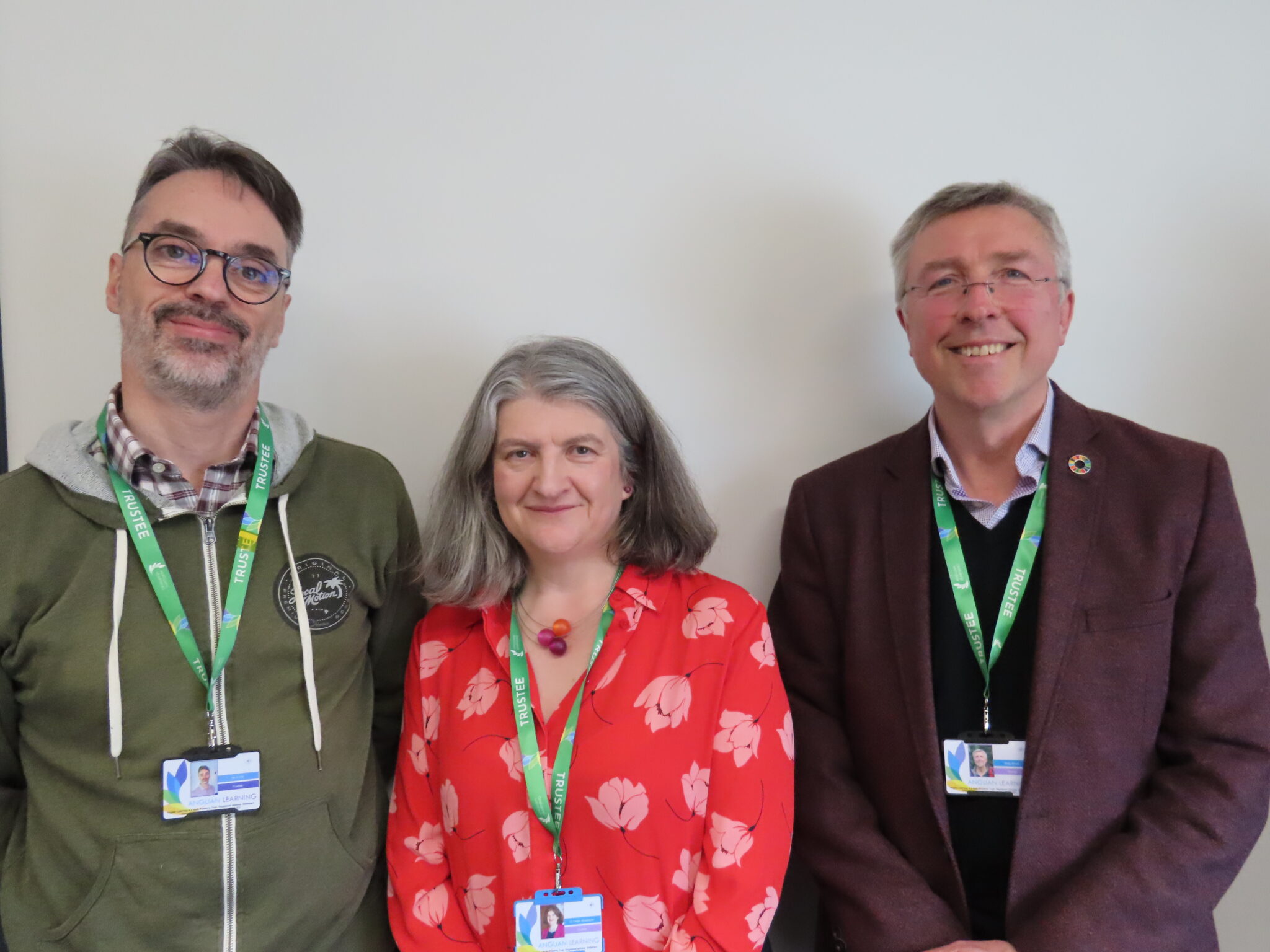 Three adults standing side-by-side smiling at the camera