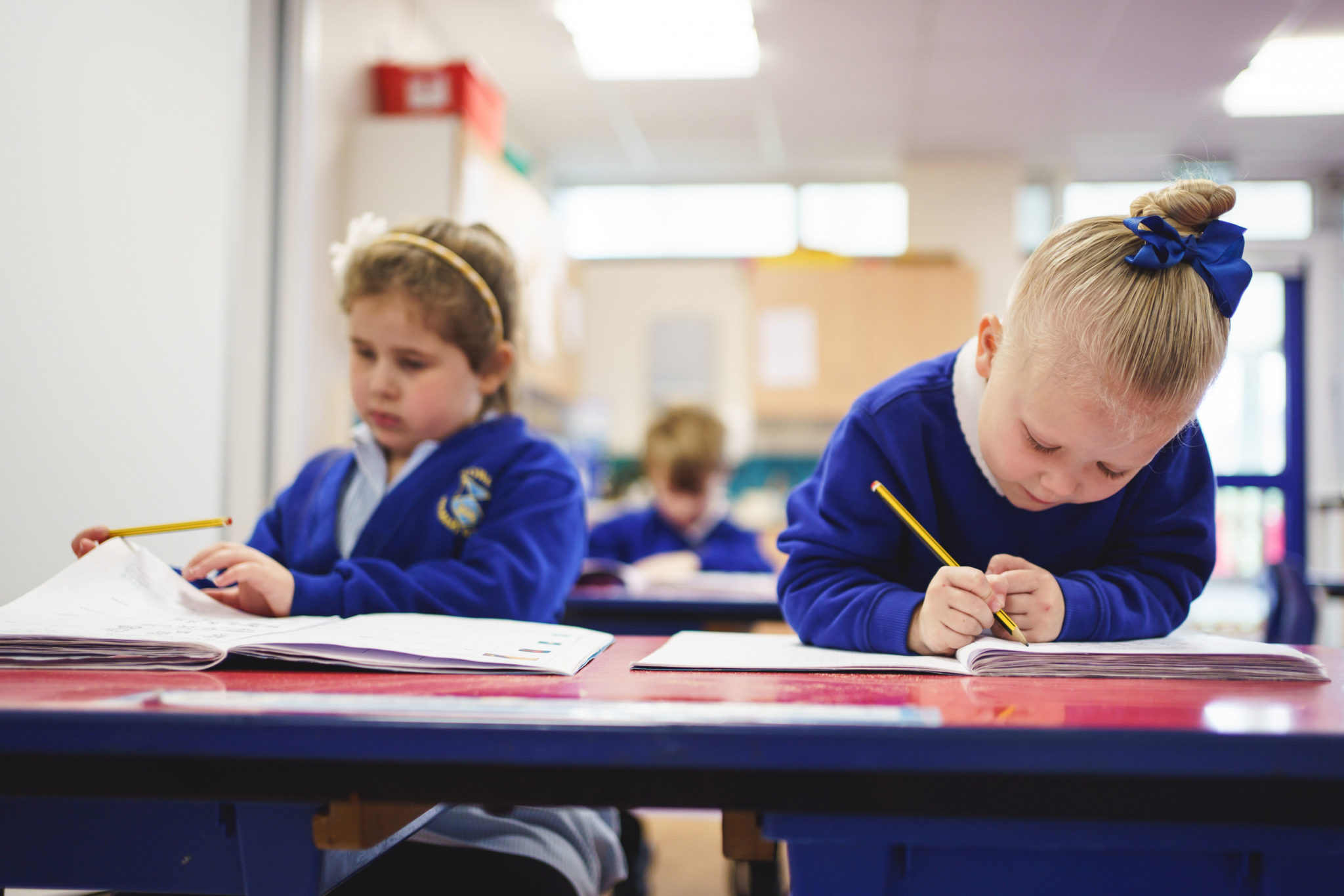 Two children writing on papers sitting at a desk