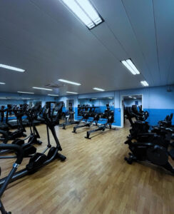 An indoor gym with gym equipment including a cycling machine and running machines