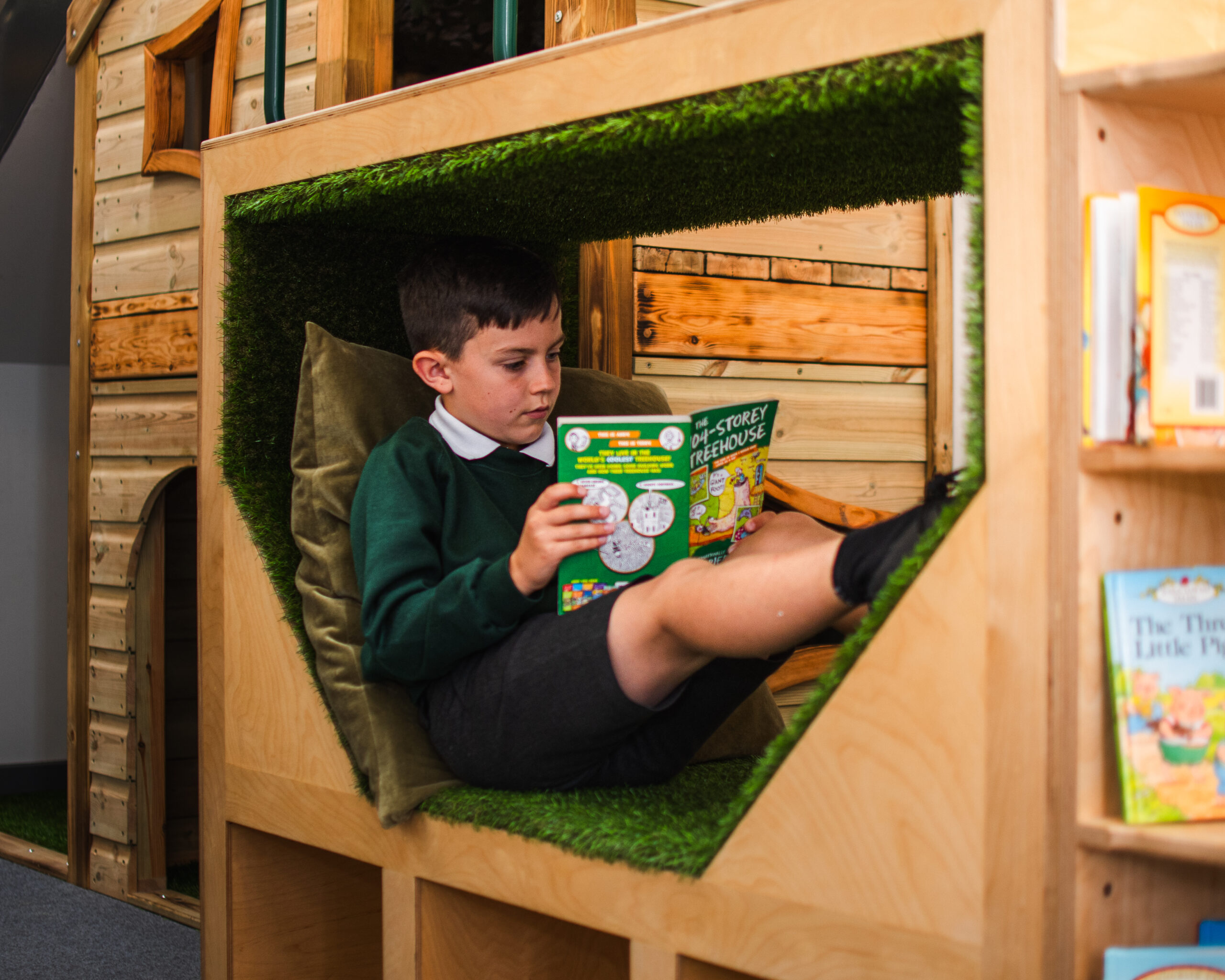 A child sitting in a library reading a book