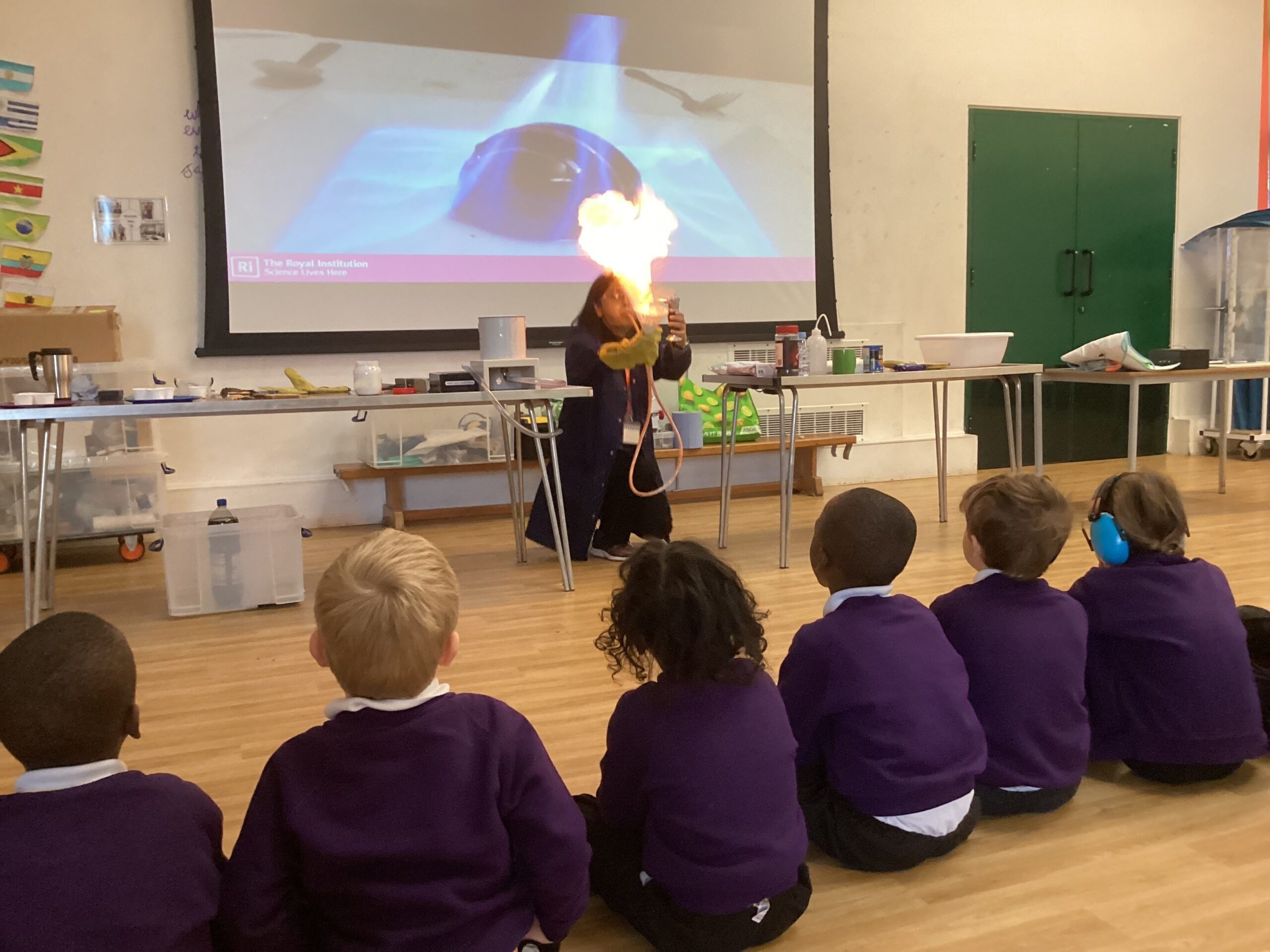 A group of children watching an adult create a large flame