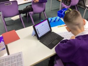 A pupil iis sitting at a desk with an iPad.