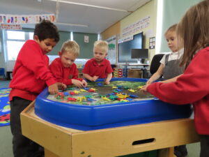 Four children playing on a table filled with toys