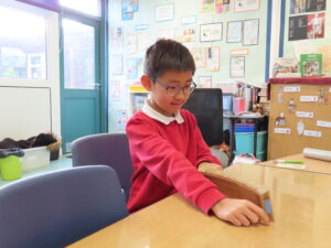 A child sitting at a desk measuring a distance on a ruler