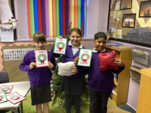 Four pupils are smiling at the camera and holding up a piece of paper.