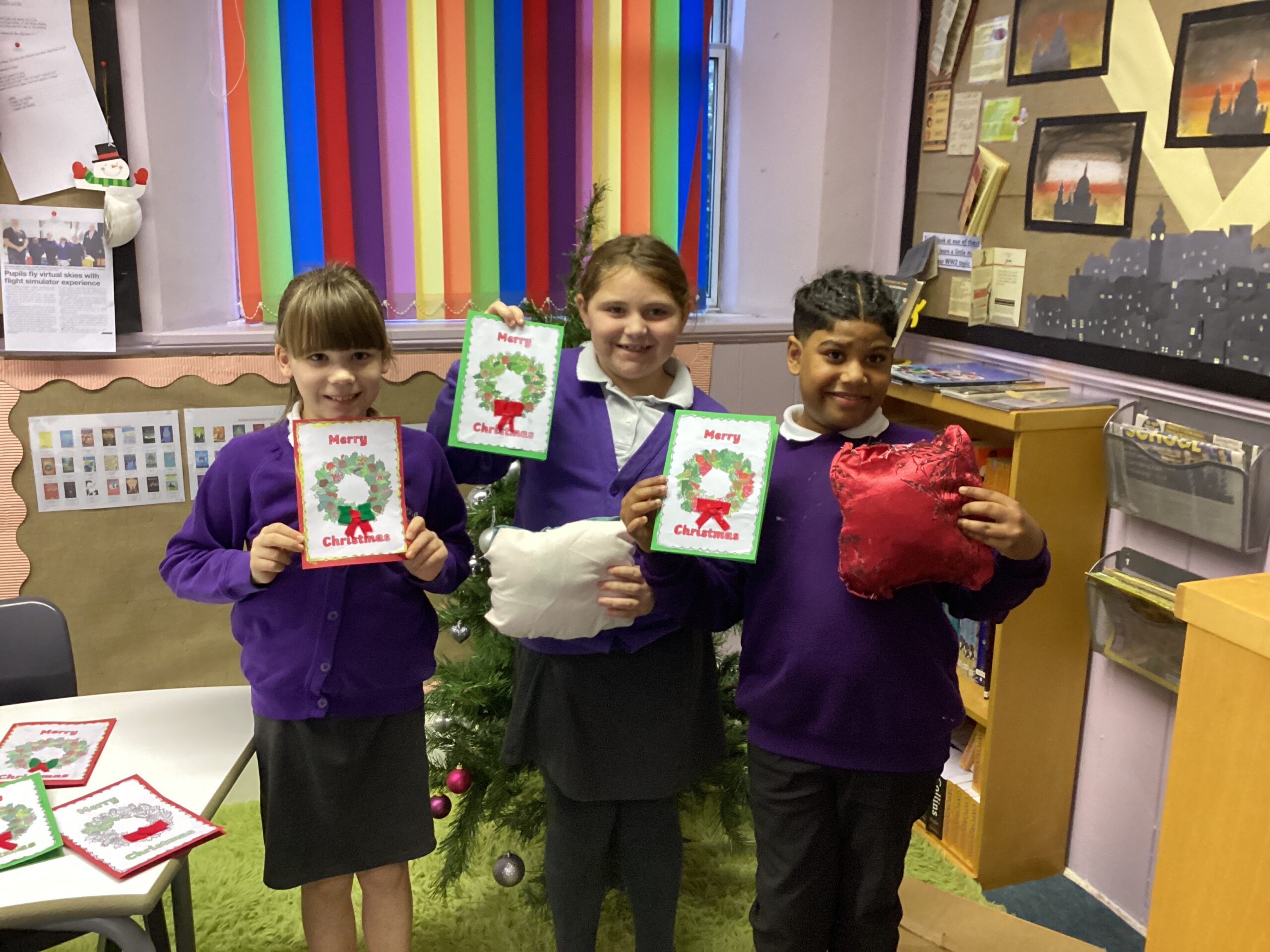 Four pupils are smiling at the camera and holding up a piece of paper.