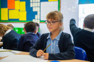 A young child wearing glasses sitting at a desk