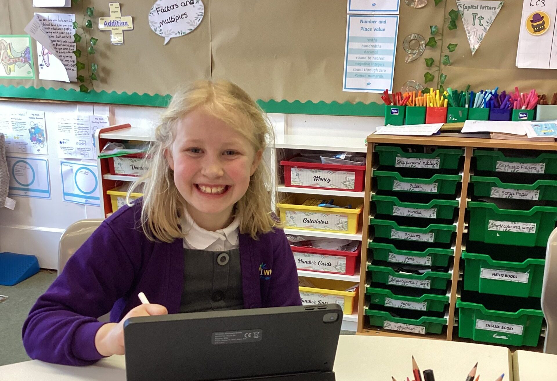 A child using an iPad smiling at the camera