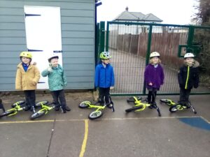 Five pupils wearing helmets and standing next to a bike