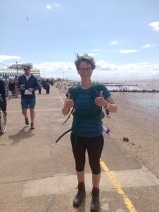 A person standing on a beach with two thumbs up