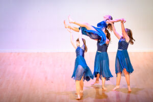 Three children holding up another child as part of a dance routine