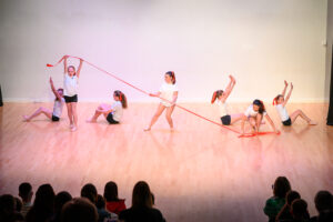 A group of children dancing with a red ribbon