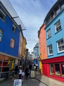 A group of people walking down a street with brightly coloured buildings.