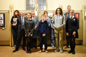 Group of adults and pupils standing in front of artwork.