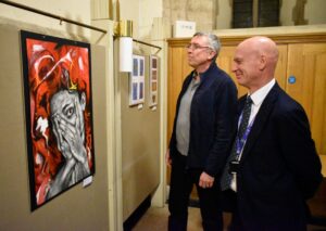 Two adult men looking at artwork.