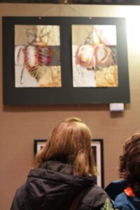 Two pieces of artwork being viewed by two people.