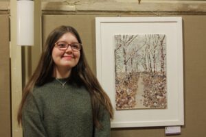 A pupil standing beside of artwork of bitch trees either side of a path.