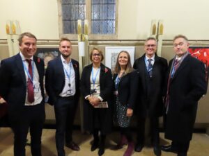 Six secondary school principals photographed in a group in front of artwork.