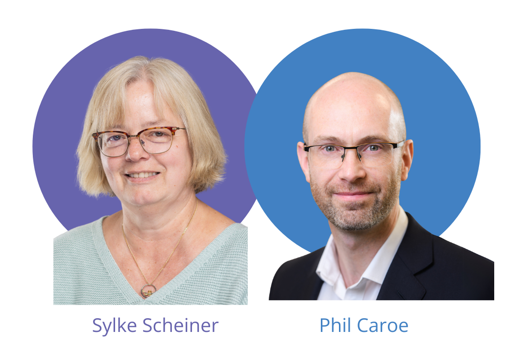 New trustees SS + PC Website A woman with blonde hair and glasses is next to a man wearing glasses and a black suit. They are both smiling.