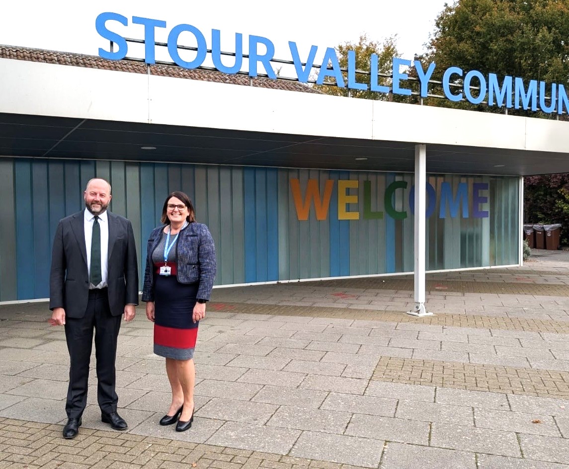 SVCS Headteacher and MP Nick Timothy A man and a woman are standing in front of school building. The building has a sign which reads 'Stour Valley Community'.